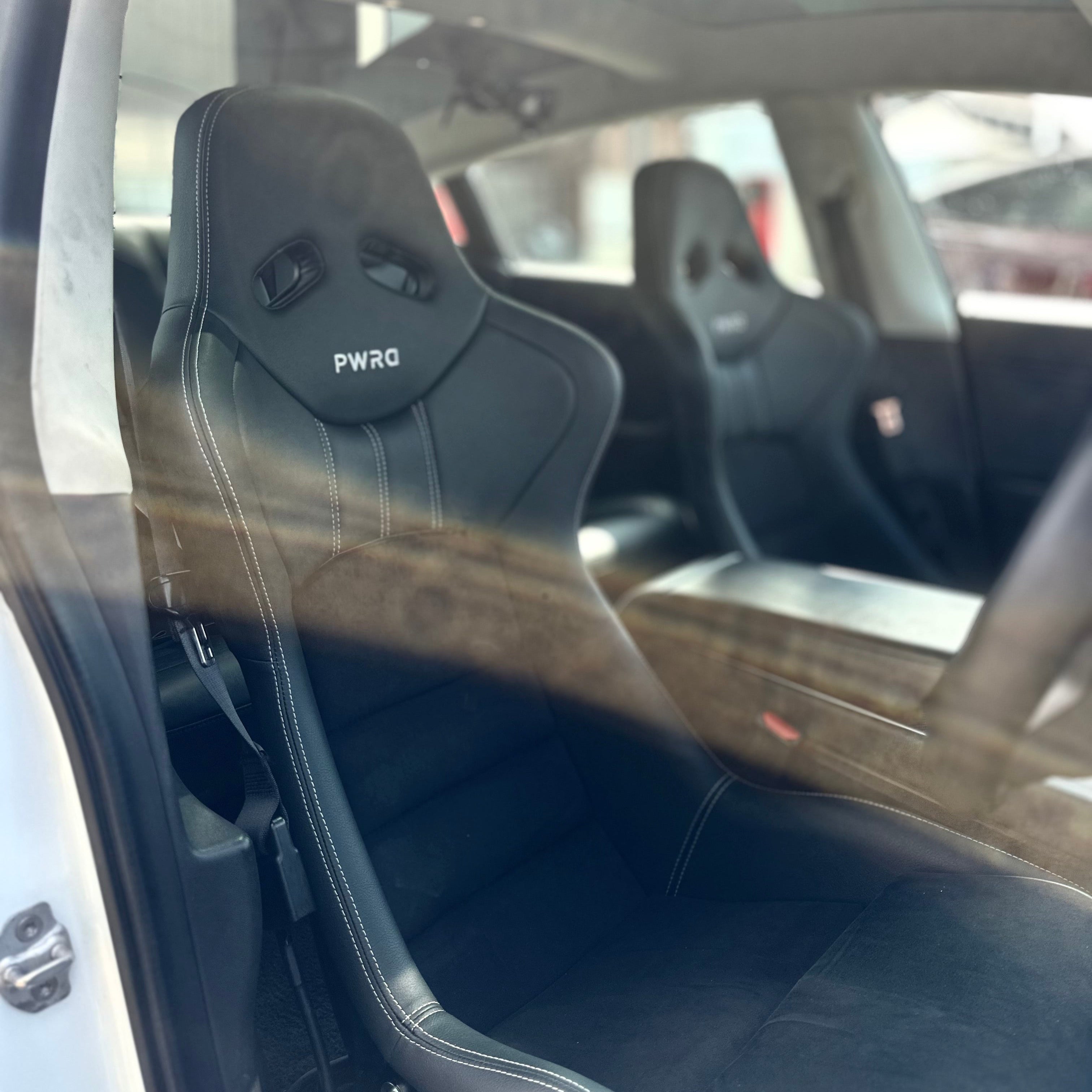 Black racing seat with 'PWRD' branding inside a car.